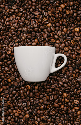 white coffee cup lies in roasted coffee beans of the highest standard