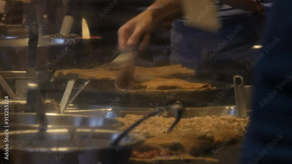 Chefs hands in the fast food kiosk prepare omelets, pancakes, noodles and other delicious dishes. Side view of women and men cooks four hands Chefs hands in the fast food kiosk prepare omelets, pancakes, noodles and other delicious dishes. Side view of women and men cooks four hands