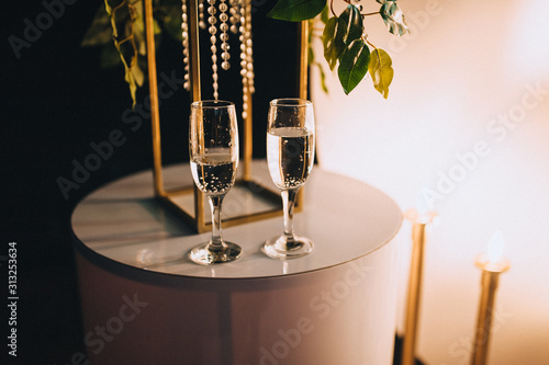 Two filled glasses with bubbly champagne stot on the table. Romantic evening in a wonderful evening atmosphere with alcohol. Photography, concept. photo