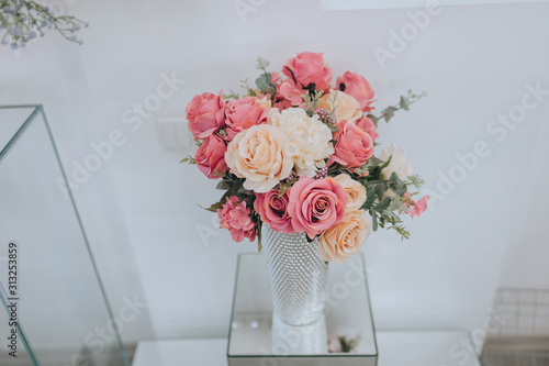 Closeup wedding bouquet of colorful roses stands in a glass vase. Wedding flowers, decorations, details, accessories. Photography, concept.