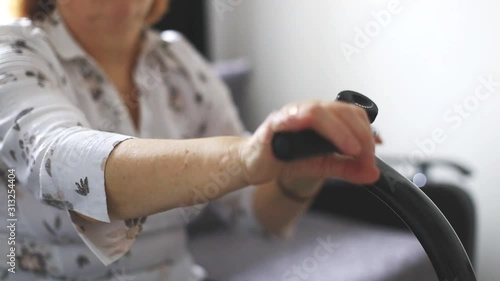 Senior woman doing home exercises for wrist at a medical device, physiotherapy