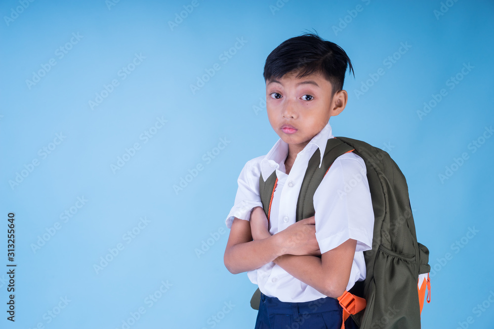An Asian Muslim school boy wearing white shirt, blue pants school uniform and backpack over blue background. Back to school concept. Isolated. Landscape orientation. An Asian Muslim school boy wearing white shirt, blue pants school uniform and backpack over blue background. Back to school concept. Isolated. Landscape orientation.