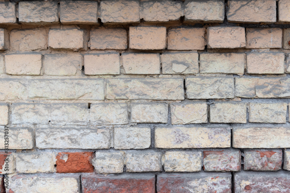Old ragged brick painted peeling walls. Texture of uneven brickwork. Old ragged brick painted peeling walls. Texture of uneven brickwork.