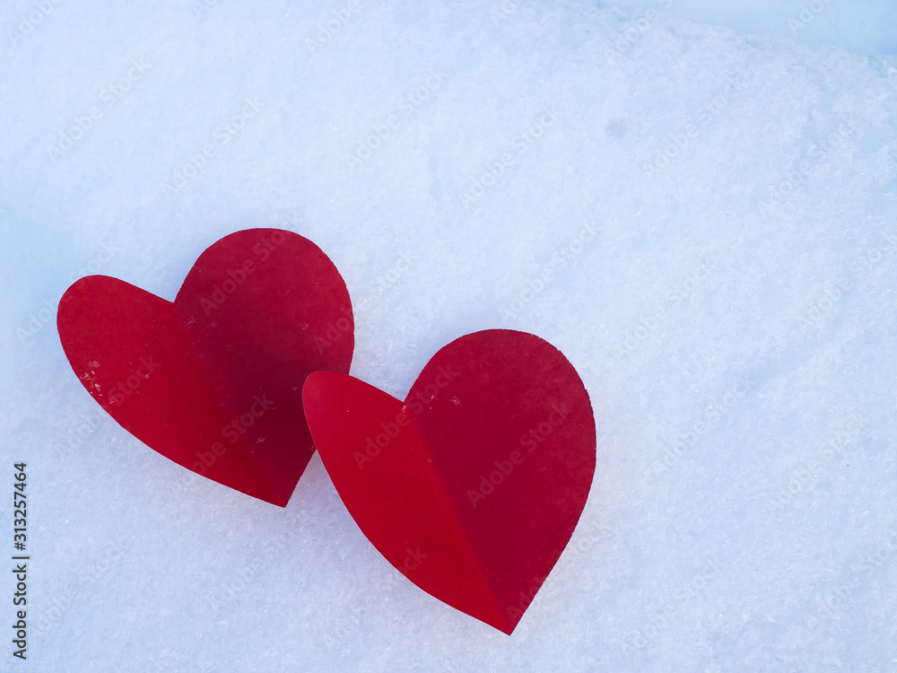 Fototapeta premium Red paper hearts on white snow as a symbol of love and warmth.