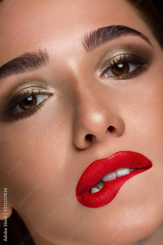 Close-up of a red-haired girl with fashionable evening make-up. Sensual plump lips with red lipstick, dark shadows on the eyelids and thick eyebrows. The fatal image of a beautiful woman. Close-up of a red-haired girl with fashionable evening make-up. Sensual plump lips with red lipstick, dark shadows on the eyelids and thick eyebrows. The fatal image of a beautiful woman.