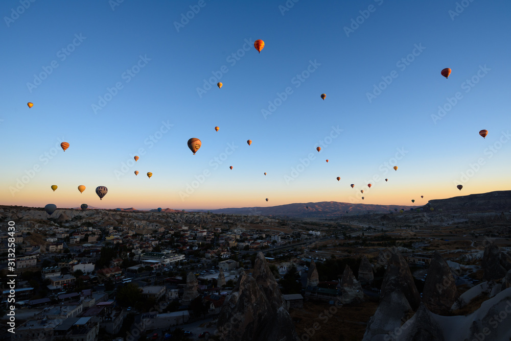 Hot air balloons flying over rocky Cappadocia landscape in Goreme, Turkey