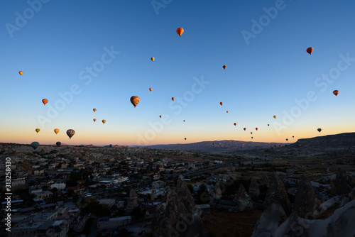 Hot air balloons flying over rocky Cappadocia landscape in Goreme, Turkey
