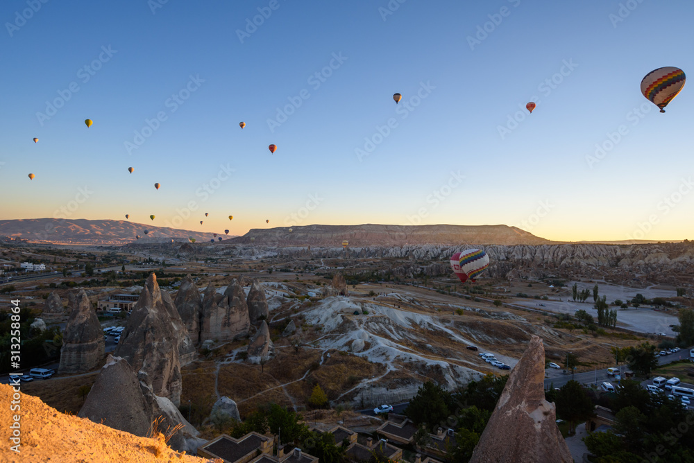 Hot air balloons flying over rocky Cappadocia landscape in Goreme, Turkey Hot air balloons flying over rocky Cappadocia landscape in Goreme, Turkey