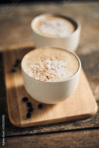 Hot coffee cup and coffee beans on wooden table..