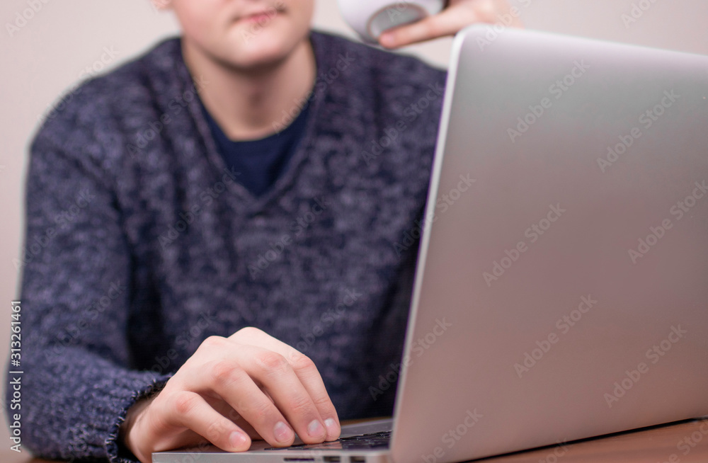 young man working at laptop with cup of coffee on light background young man working at laptop with cup of coffee on light background