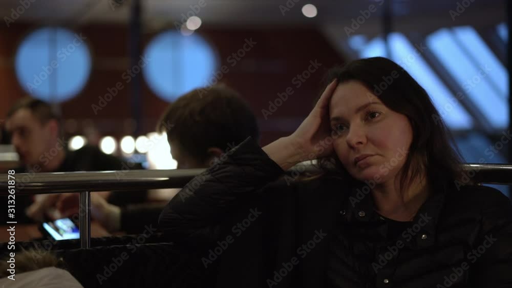 thoughtful woman sits in ferry cafe and dreams against tourists eating dishes and drinking close view thoughtful woman sits in ferry cafe and dreams against tourists eating dishes and drinking close view