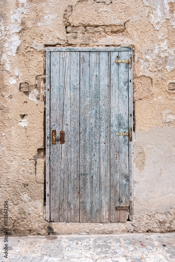 Old closed wooden rectangular door, iron and lock. Stone wall. Italy.