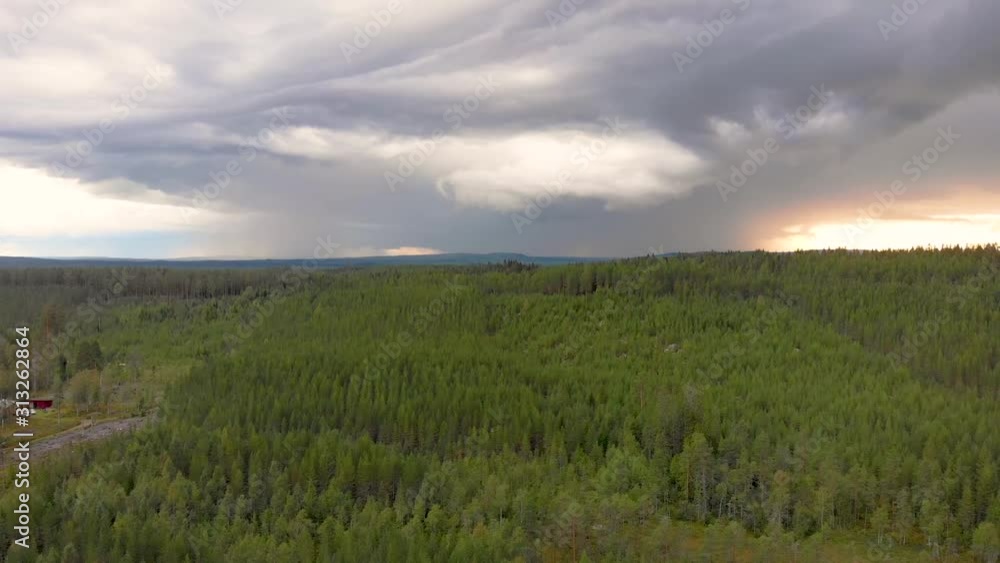 Backwards drone flight over pine tree forest at sunset with dark clouds at Dalarna county, Vansbro municipality , Sweden Backwards drone flight over pine tree forest at sunset with dark clouds at Dalarna county, Vansbro municipality , Sweden