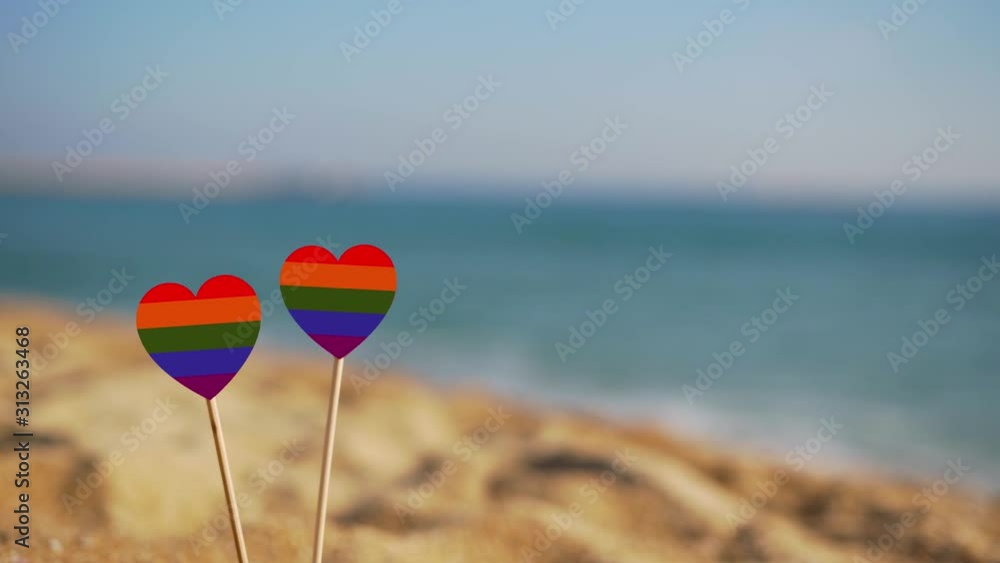 two hearts of the color of the gay flag on a background of sea waves. two hearts of the color of the gay flag on a background of sea waves.