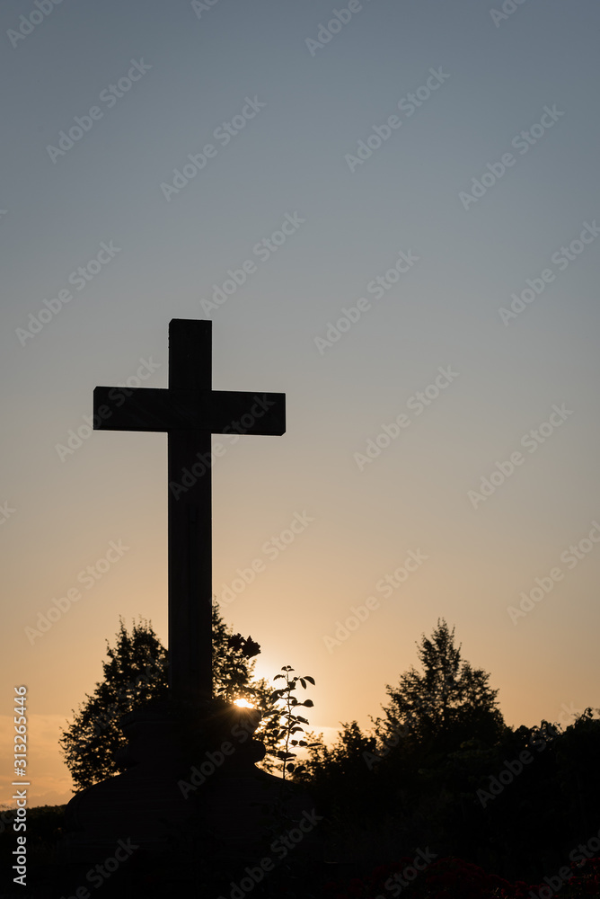 christian cross backlit from the evening sun and blue and orange sky