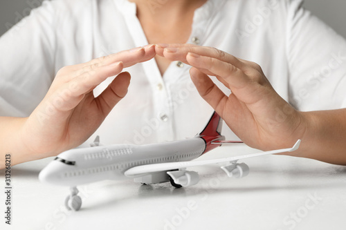 Woman covering toy plane at white table  closeup. Logistics and wholesale concept