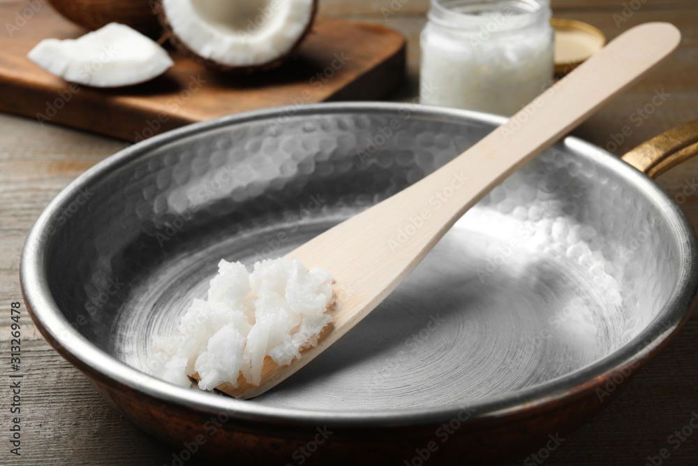 Frying pan with coconut oil and wooden spatula on wooden table, closeup. Healthy cooking Frying pan with coconut oil and wooden spatula on wooden table, closeup. Healthy cooking