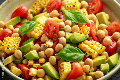 Avocado chickpea salad with grilled sweet corn, tomato and basil. Healthy vegan food