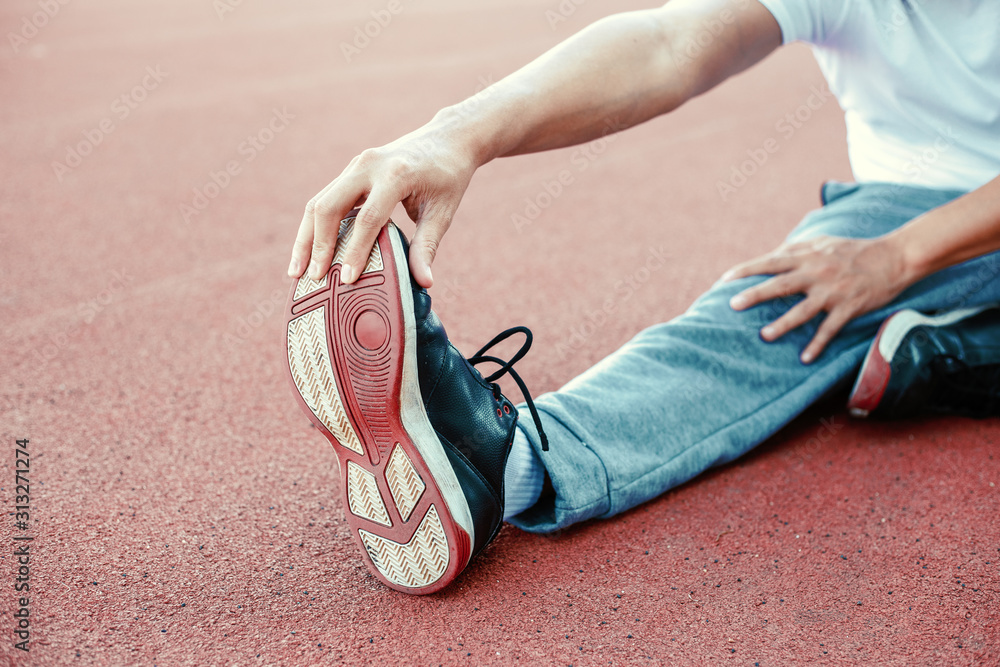 Full length portrait of a athletic man stretching at sport stadium.