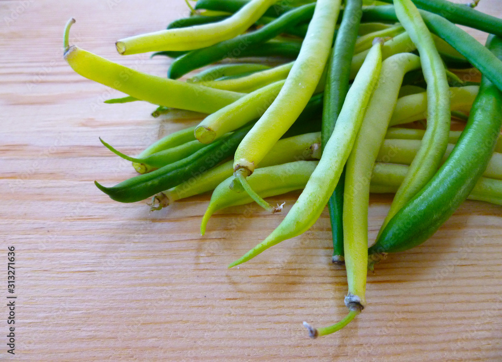 Green and yellow bean pods of asparagus on old rustic wooden table. Freshly harvested raw beans on wooden background. Closeup, selective focus. Green and yellow bean pods of asparagus on old rustic wooden table. Freshly harvested raw beans on wooden background. Closeup, selective focus.