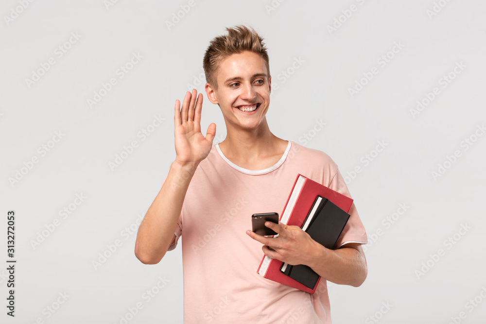 Smiling pretty young man in a pink t-shirt with books and files. Smiling pretty young man in a pink t-shirt with books and files.