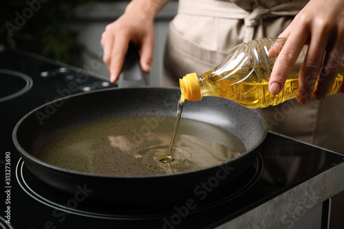 Foto Woman pouring cooking oil from bottle into frying pan, closeup