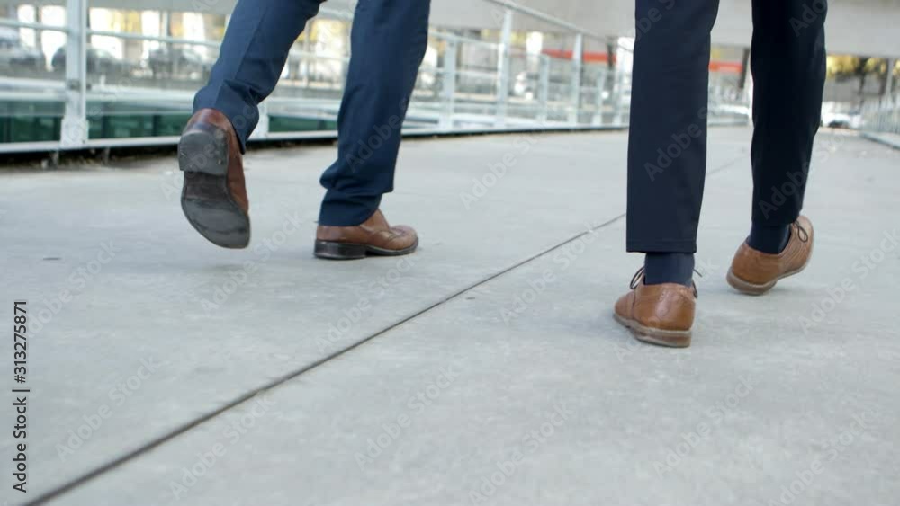 Low section of businessmen walking on street. Cropped shot of professional business people in formal wear walking together on street, tracking shot. Cooperation concept Low section of businessmen walking on street. Cropped shot of professional business people in formal wear walking together on street, tracking shot. Cooperation concept