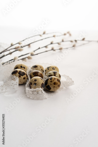 quail eggs with lace and willow branches on a white background. Congratulations on Easter. Place for text