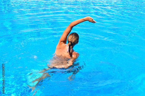 Exercise in the pool. Girl doing gymnastic exercises in the water. Active water sports. The Aqua-fitness for women.