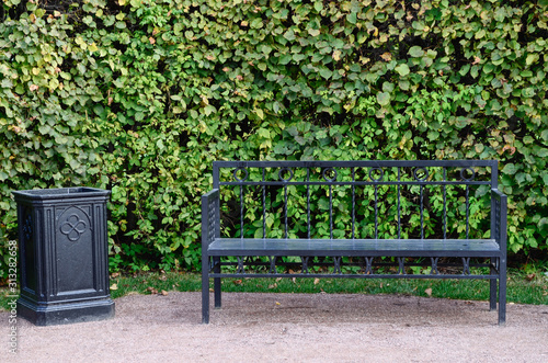 Park bench, white bench, black cast-iron bench. Handbag on the bench.