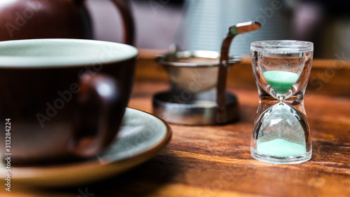 Small sand clock, equipment for making dry flower with tea stainless steel tea strainer infuser and a porcelain vintage cup.