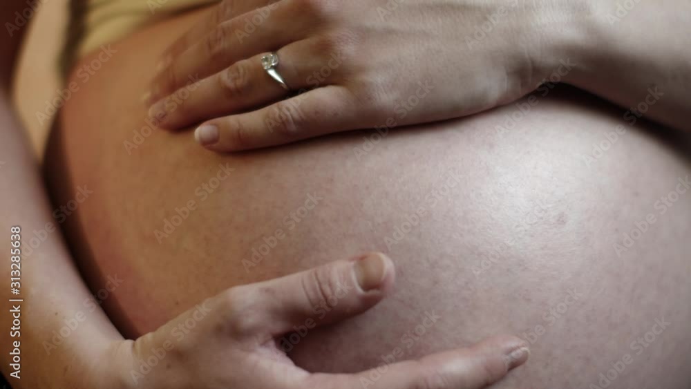 Caressing hands on a belly of a pregnant mother Caressing hands on a belly of a pregnant mother