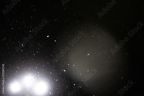 Snow and bokeh in the light of a lantern on a black background