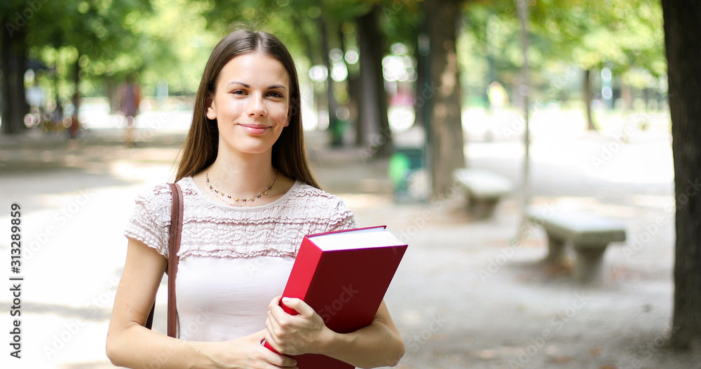 Smiling student outdoor holding a book Smiling student outdoor holding a book