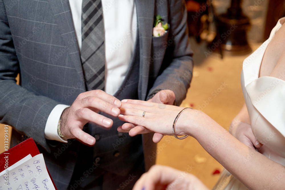 Groom Dresses the Ring for the Bride, close-up in marriage registry office Groom Dresses the Ring for the Bride, close-up in marriage registry office