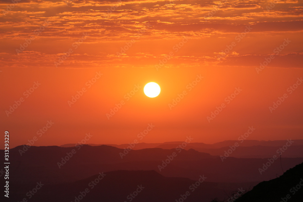 Landscape View of a sun during the sunset with orange background and Mountains