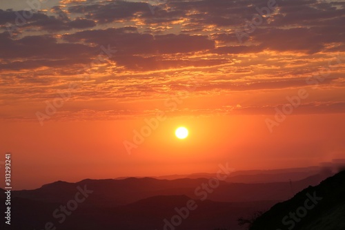 Landscape view of the sunrise from top to the mountain with orange color shade in the background with sun