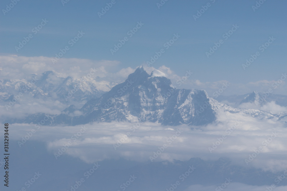 A beautiful photo of a mountain with glacier and snow on it from a height above the clouds