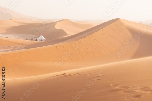 Camp with tent in the desert among sandy dunes. Sunny day in the Sahara during a sand storm in Morocco Picturesque background nature concept