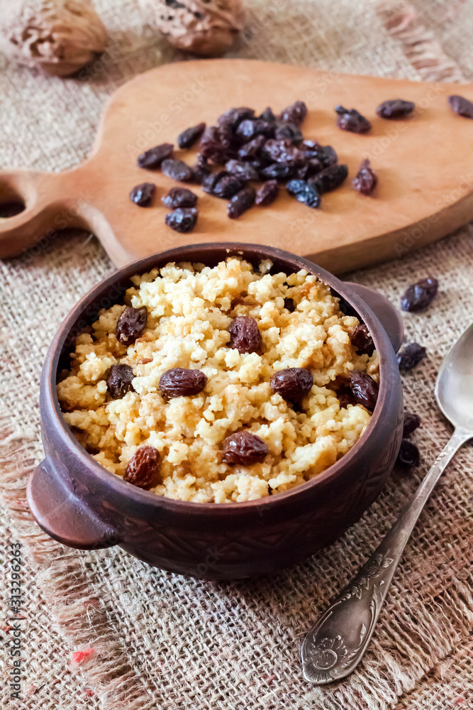 Sweet millet porridge with dark raisins in ceramic rustic bowl Sweet millet porridge with dark raisins in ceramic rustic bowl