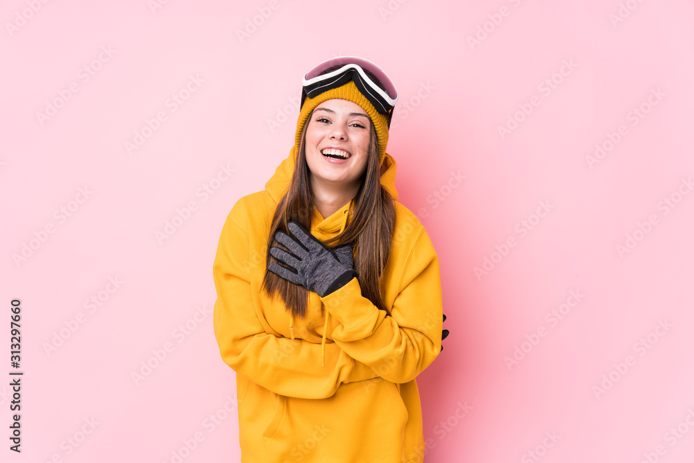 Young caucasian woman wearing ski clothes isolated laughs out loudly keeping hand on chest.