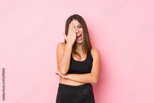 Young fitness caucasian woman isolated having fun covering half of face with palm.