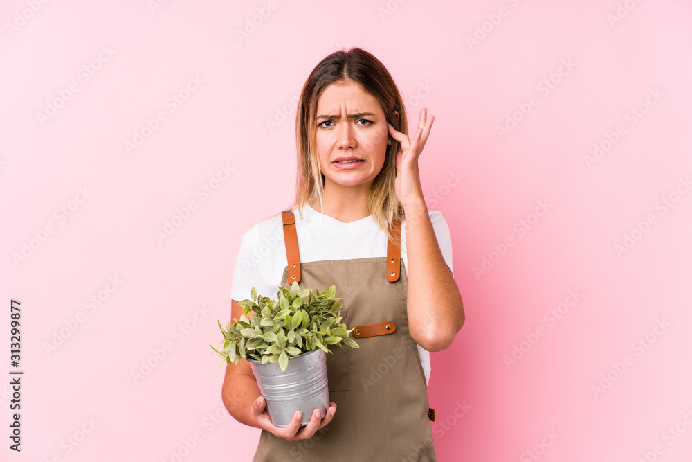 Young caucasian gardener woman in a pink background covering ears with hands. Young caucasian gardener woman in a pink background covering ears with hands.