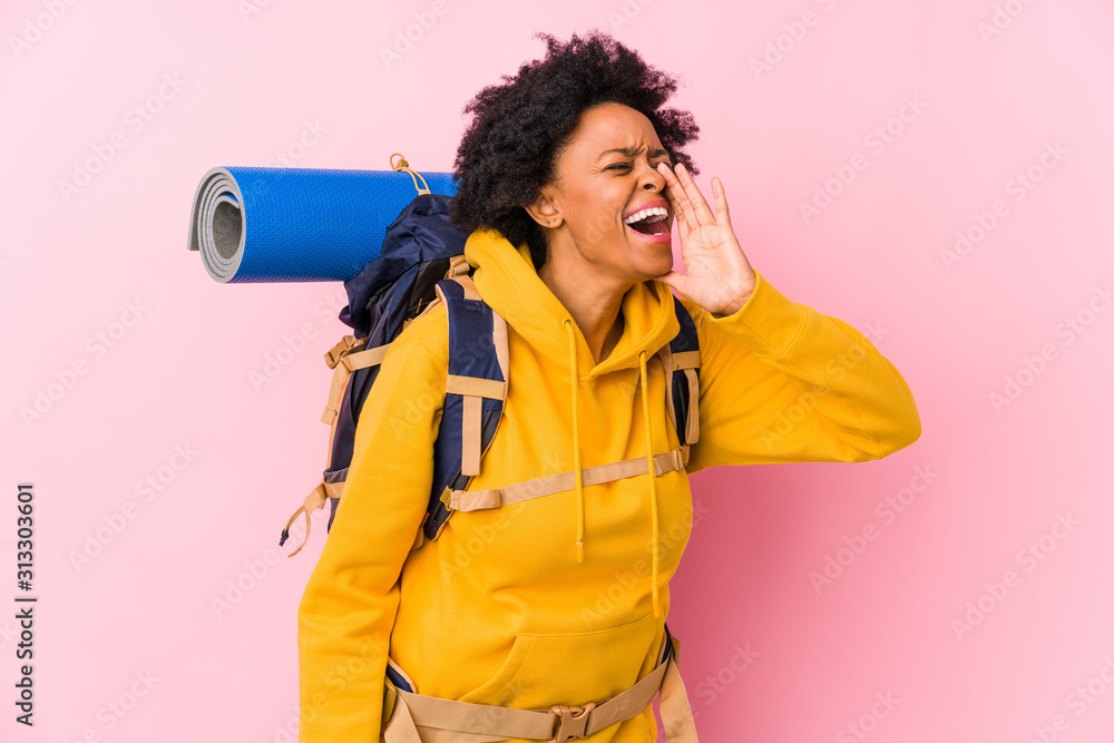 Young african american backpacker woman isolated shouting and holding palm near opened mouth.