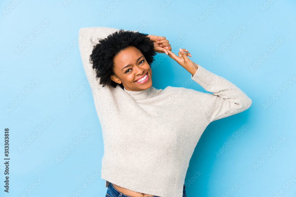 Middle aged african american woman against a blue background isolated stretching arms, relaxed position. - obrazy, fototapety, plakaty 