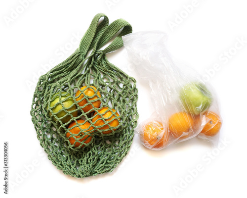Green Hand-Made Crochet Eco-Friendly String Shopping Bag with Green Apples and Tangerines  VS Plastic Bag on White Background Flat Lay. Concept of Ecology, Environmental Protectio                     