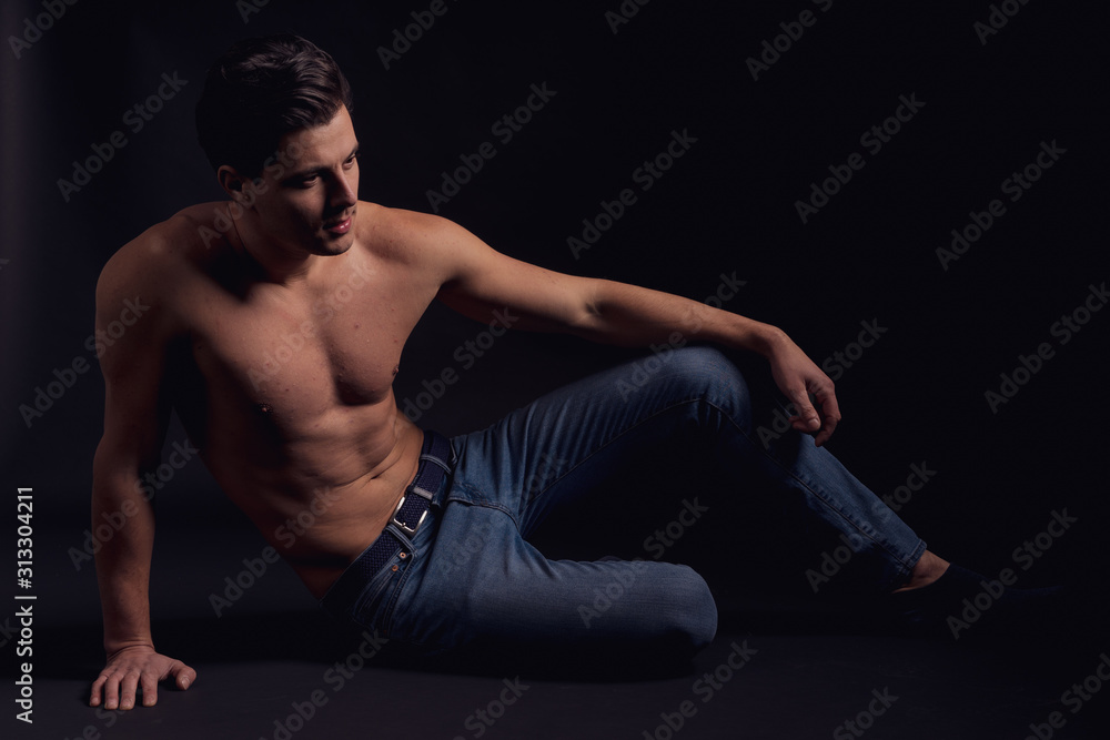 Stylish guy without a shirt on the floor looking to the side and thought Stylish guy without a shirt on the floor looking to the side and thought