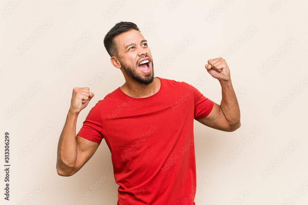Young south-asian man raising fist after a victory, winner concept. Young south-asian man raising fist after a victory, winner concept.