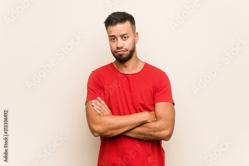 Young south-asian man unhappy looking in camera with sarcastic expression.