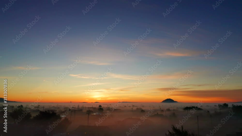 Aerial Rising Shot over Telephone Lines and Foggy Neighborhood in Orange Sunrise
